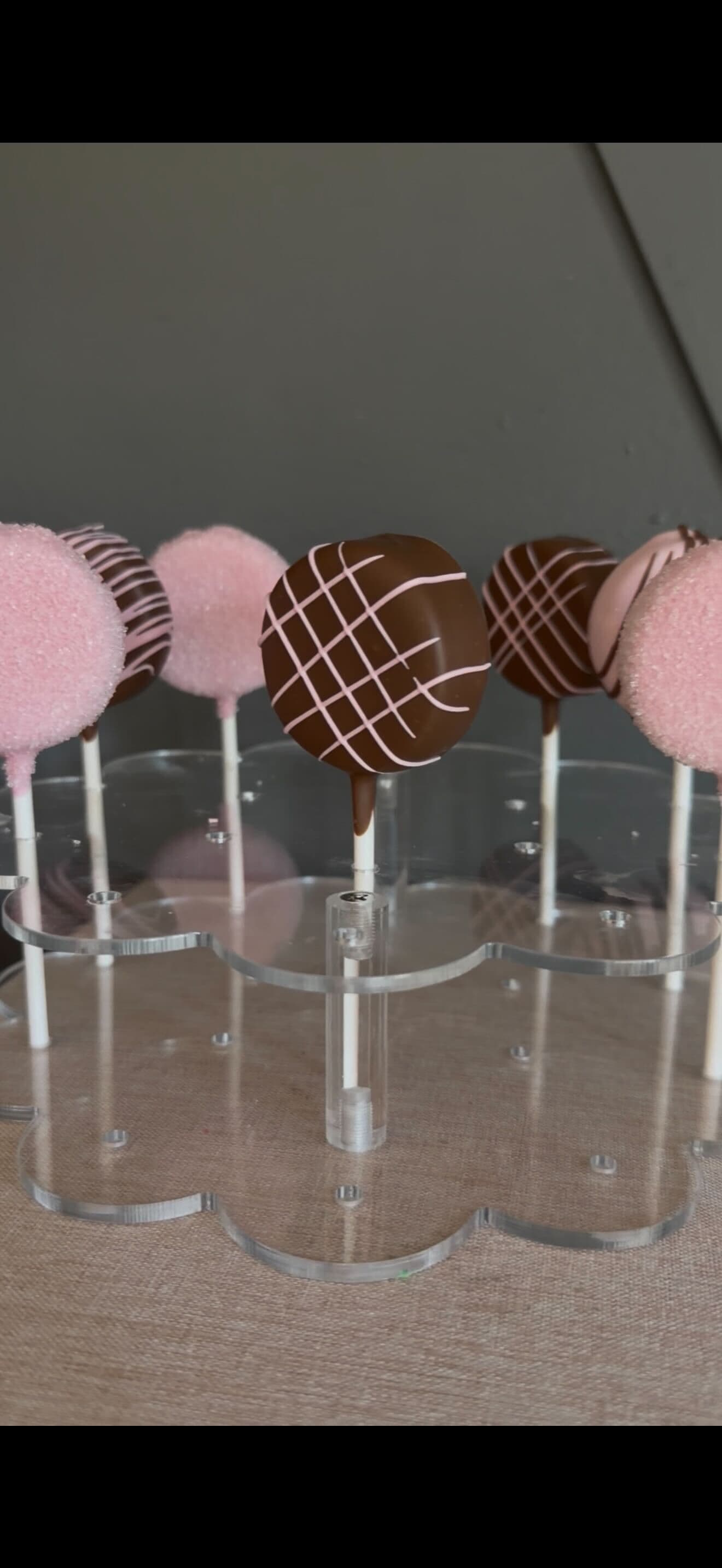 Assorted pink and chocolate cake pops displayed in a clear holder