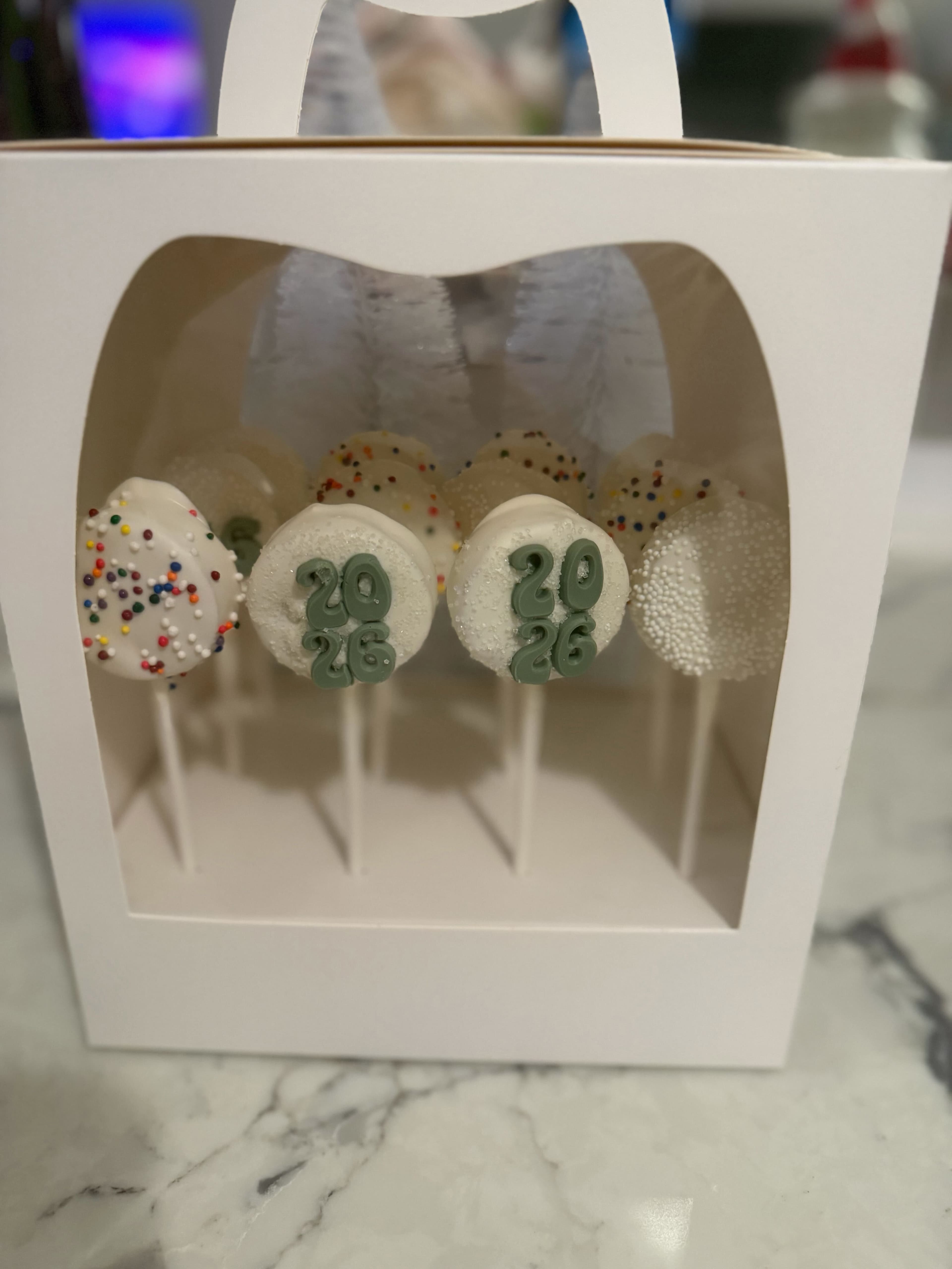 White cake pops with colorful sprinkles and a numbered topper for a celebration
