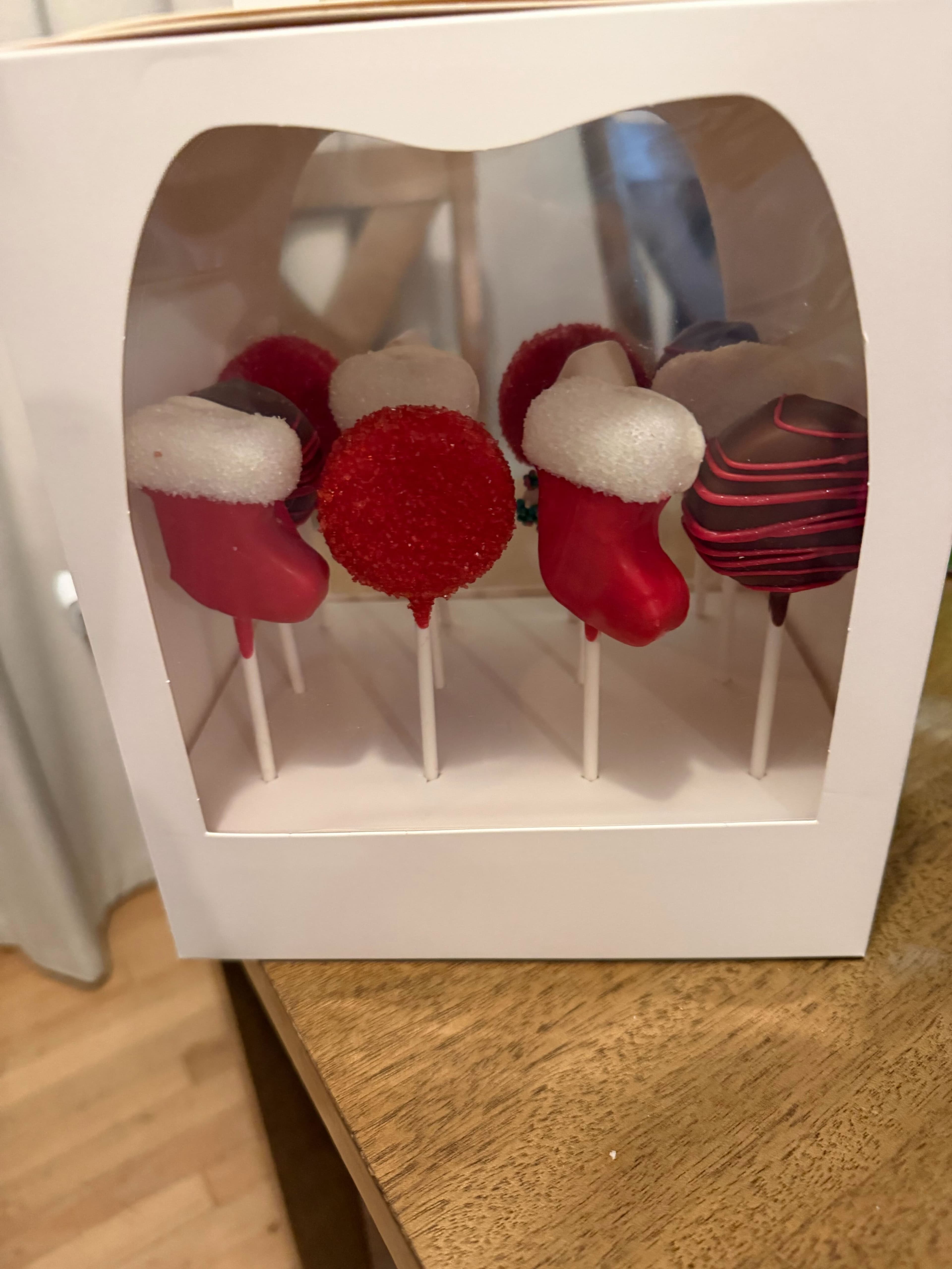 Holiday-themed cake pops in red and white with festive decorations