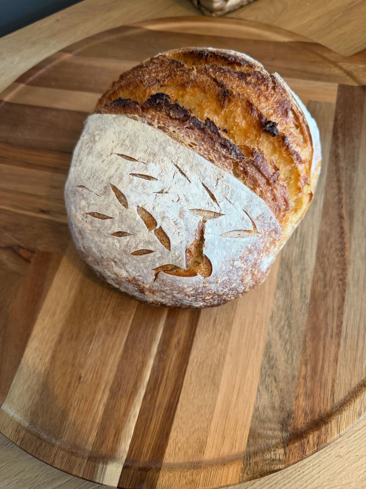 Hand-scored artisan sourdough boule on a wooden board